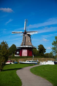 Dokkum, Friesland, The Netherlands - August 17, 2018  Boats on canal and windmill on fortifications of historic town Dokkum, Friesland, The Netherlands.