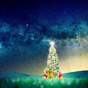 Conceptual image of Decorated Christmas tree on green landscape over night sky with stars and galaxies. .Space Image link: https://nasasearch.nasa.gov/search/images?utf8=%E2%9C%93&affiliate=nasa&query=galaxy+images