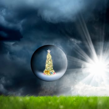Decorated Christmas tree in glass sphere floating in air over green grass landscape and stormy sky