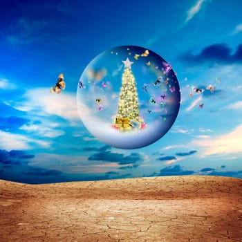 Decorated Christmas tree in glass sphere with group of butterflies floating in air over dried and cracked landscape