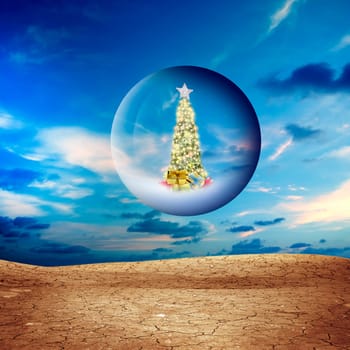 Decorated Christmas tree in glass sphere floating in air over dried and cracked landscape