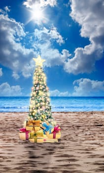 Decorated Christmas tree on sandy beach over sea with suny sky