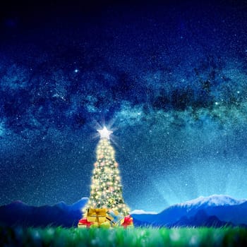 Conceptual image of Decorated Christmas tree on green landscape over night sky with stars and galaxies. .Space Image link: https://nasasearch.nasa.gov/search/images?utf8=%E2%9C%93&affiliate=nasa&query=galaxy+images