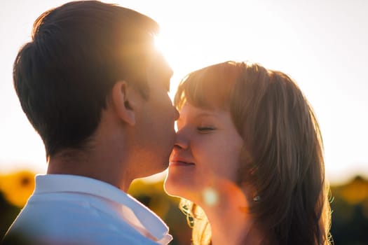 Romantic couple standing and kissing on background summer meadow sunflower sunset