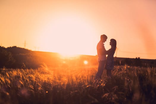 Romantic couple standing and kissing on background summer meadow sunset