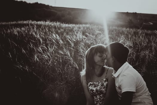 Romantic black white photo couple standing and kissing on background summer meadow sunset
