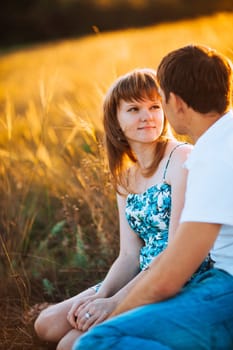 Romantic couple standing and kissing on background summer meadow sunset