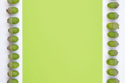 green acorns in two ribbons on green and white background with copy space in the middle