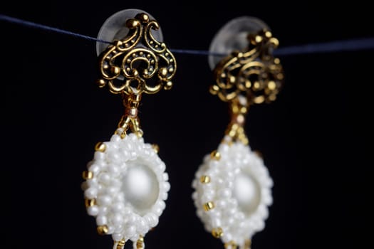 handmade jewelry made of beads in macro. earrings from white beads. earrings from stones. beautiful ornaments. earrings from red beads. ornaments on a black background