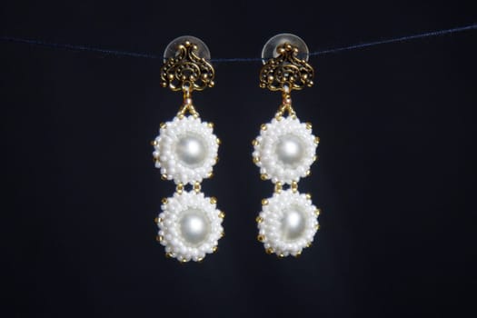 handmade jewelry made of beads in macro. earrings from white beads. earrings from stones. beautiful ornaments. earrings from red beads. ornaments on a black background