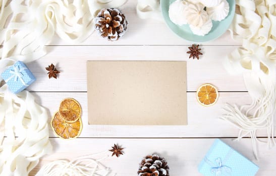 Autumn or winter composition with top view on paper sheet, white scarf, gift box and other winter accessories. Copy space blank sheet.