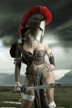 Ancient woman warrior or Gladiator posing outdoors with sword and helmet