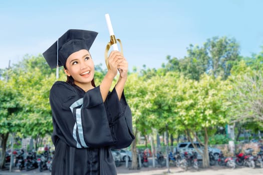 Beautiful asian student girl celebrate her graduation with cap and diploma scroll on campus