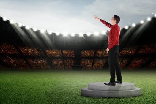 Attractive asian businessman standing and pointing to the sky on podium