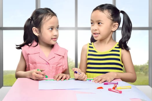 Smiling two asian girl with crayon learn to draw on class