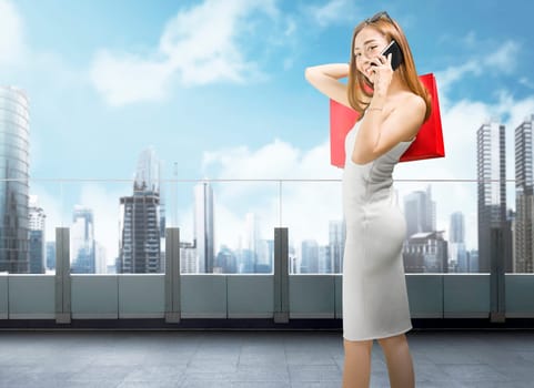 Beautiful asian woman with smartphone and red shopping bags on mall balcony
