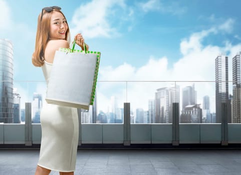 Pretty asian woman in white dress holding shopping bags on mall terrace