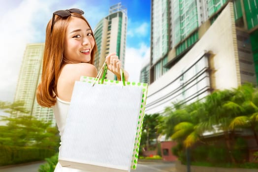 Happy asian woman carrying shopping bags after shopping at mall