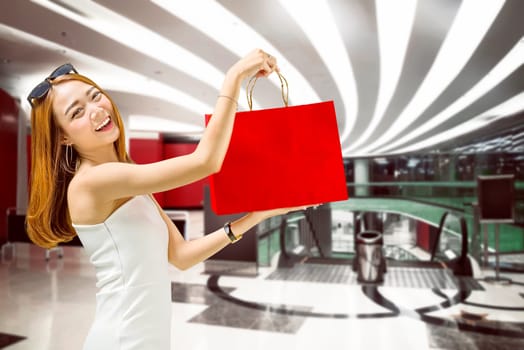 Beautiful asian woman showing her shopping bags in mall. Black friday concept