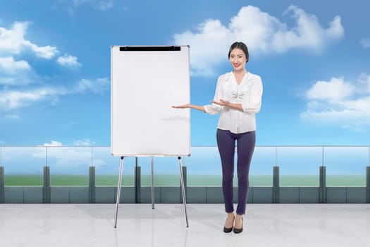 Attractive asian businesswoman in white suit showing copyspace on whiteboard