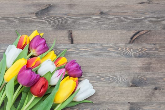 Large big bouquet of tulips on a wooden background.