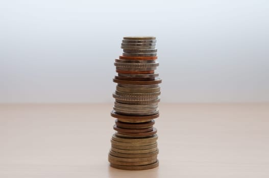 A stack of coins of different countries, different dignity, and size on the table in the center of the image.