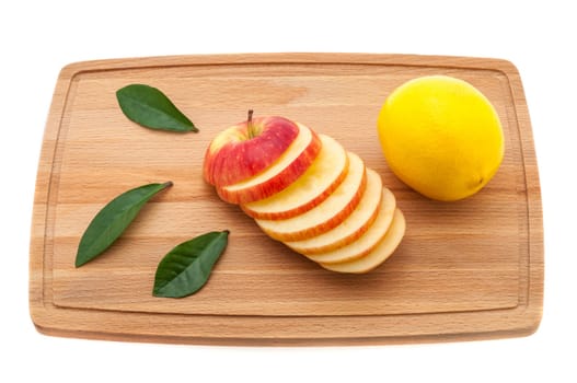 apple fresh and juicy with green leaves and lemon on a cutting board made of wood.