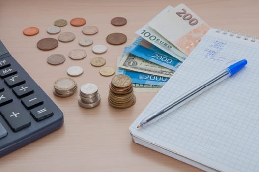 Notepad, bills, various money and a calculator on the table.