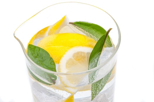 A full jug of drink from ice, lobules of juicy yellow lemon and crystal clear water.