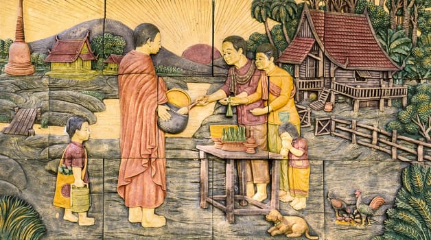 Bangkok ,Thailand - October 27, 2015 : Thai stucco art of offering food to Buddhist monks on temple wall at Wat Dan in Bangkok, Thailand