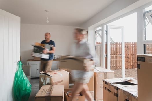 Slow shutter speed shot of a mature couple moving boxes in their new home.