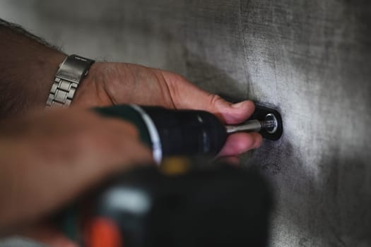 Close up shot of a man using a light-assisted power drill to put together some furniture.