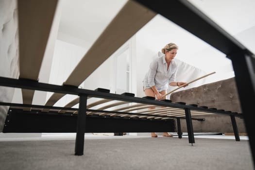 Low angle view of a mature woman setting up her bed in her new home.