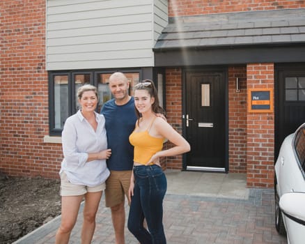 Portrait of a family with one child outside of their new home.