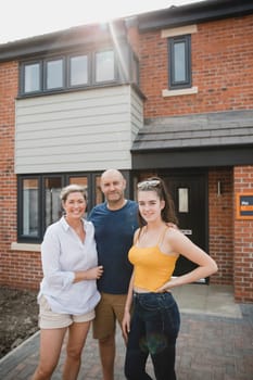 Portrait of a family with one child outside of their new home.