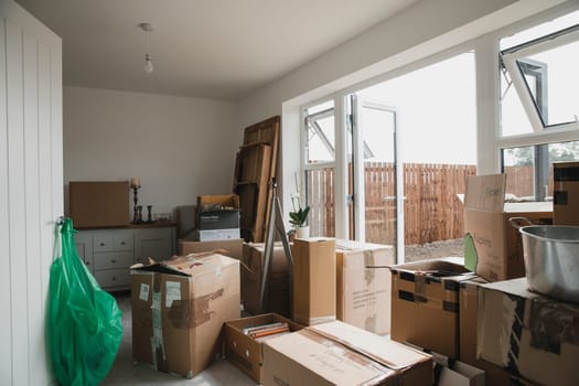 Dining room is full of furniture and cardboard boxes as a family are moving in.