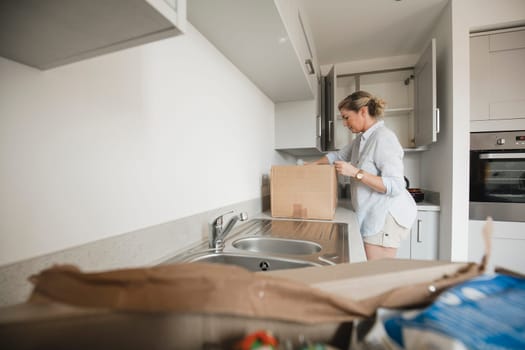 Mature woman is unpacking boxes in her new home.