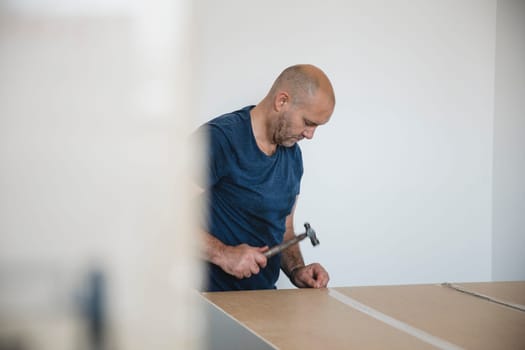Mature man is putting a wardrobe together in a new home.