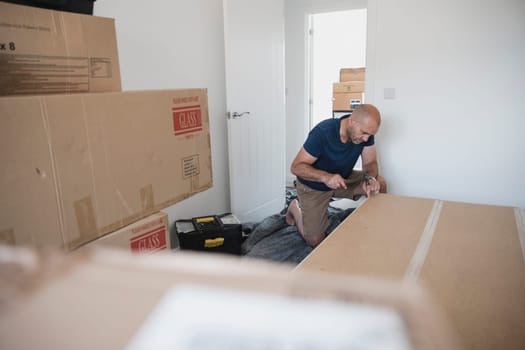 Mature man is putting a wardrobe together in a bedroom of a new home.