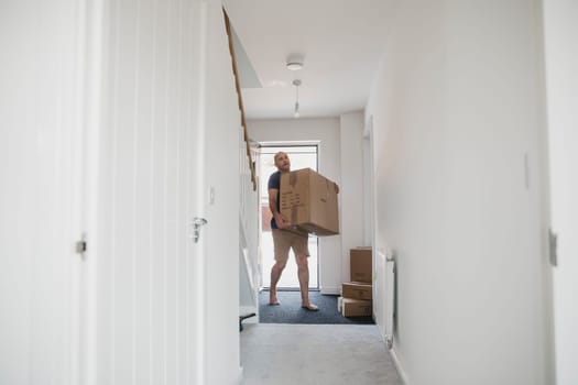 Mature man is carrying boxes in to his new home.