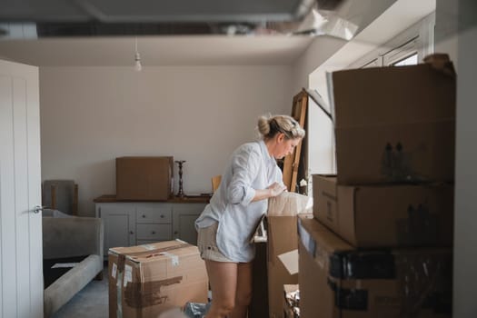 Mature woman is unpacking boxes in her new home.
