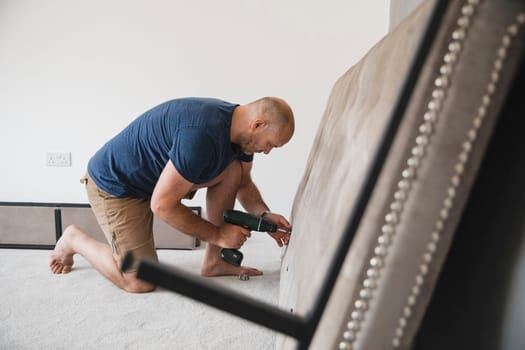 Mature man is building a bed in his new home.