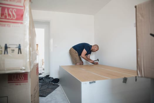 Mature man is putting a wardrobe together in a bedroom of a new home.