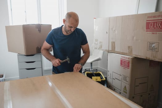 Mature man is putting a wardrobe together in a bedroom of a new home.