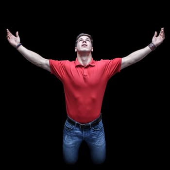 Young man looking up in a kneeling position with raised hands