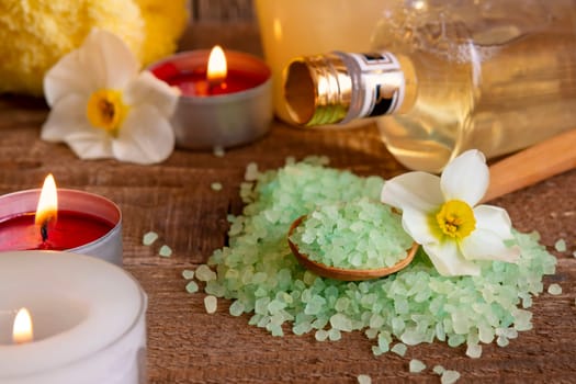 Spa still life with bath salt candles and flowers on wodden table. Body beauty and care concept.