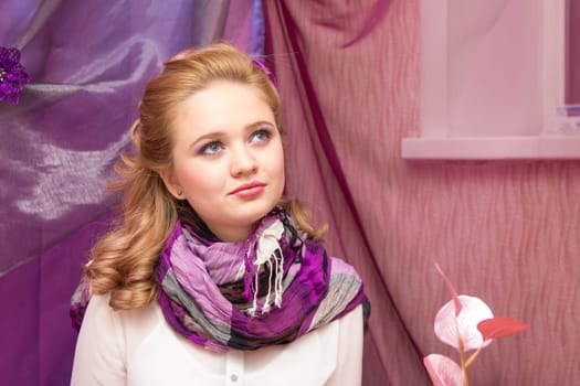 A young blonde girl in a purple scarf looking at the camera