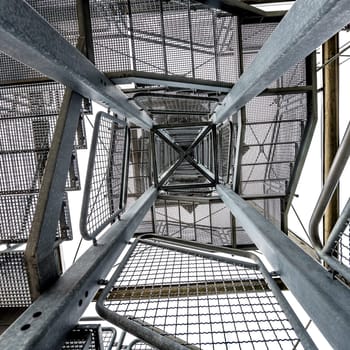 Square metal tower construction with staircase against white background