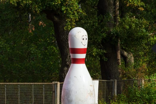 Bowling cone with white and red stripes in front of green background