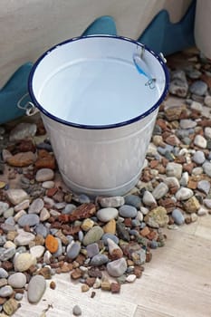 Retro style metal bucket at rocks pebbles